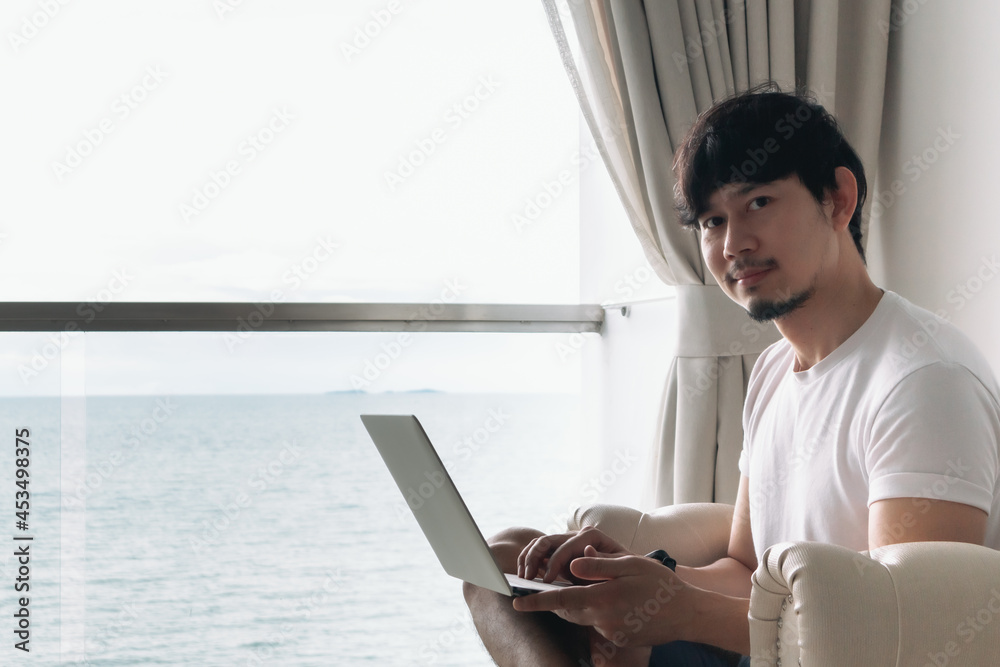 Happy Asian man work in the hotel with sea view. Staycation concept. Happy Asian man work in the hotel with sea view. Staycation concept.