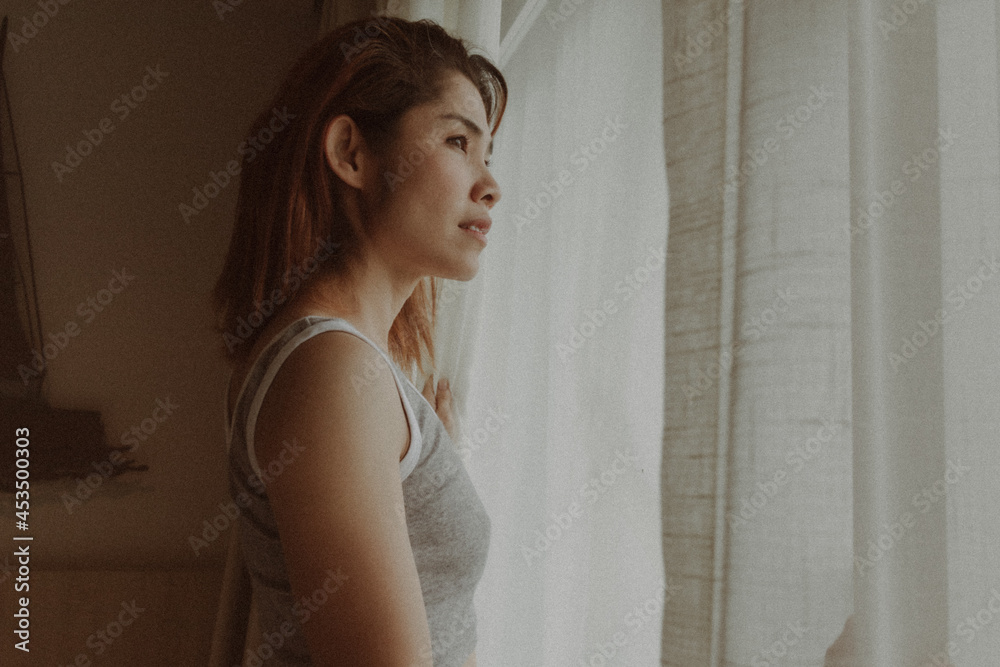 Attractive Asian woman look at the view behind the curtain in the hotel. Attractive Asian woman look at the view behind the curtain in the hotel.