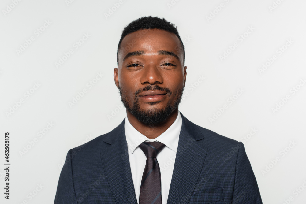 smiling african american businessman in suit with tie isolated on grey smiling african american businessman in suit with tie isolated on grey