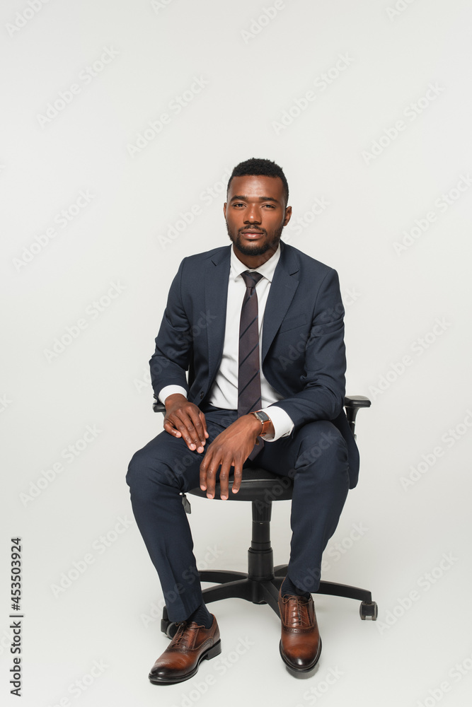 african american businessman in suit sitting in office chair isolated on grey african american businessman in suit sitting in office chair isolated on grey