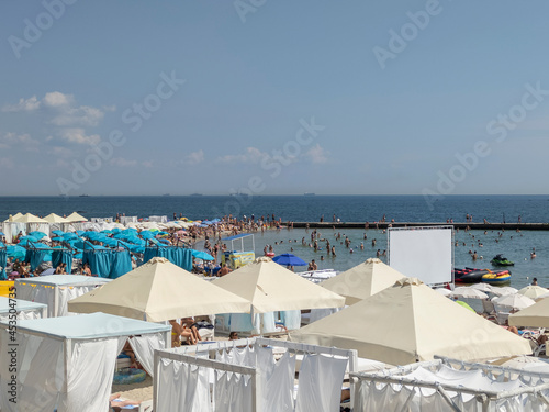 Umbrellas and people on a public beach on a sunny day. Odesa  Ukraine