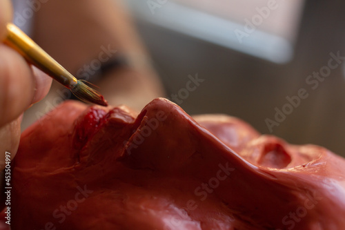 Man painting with a brush the lips of a woman's bust. Making handicrafts. Selective focus. Copy space. Homemade. Hobbies.