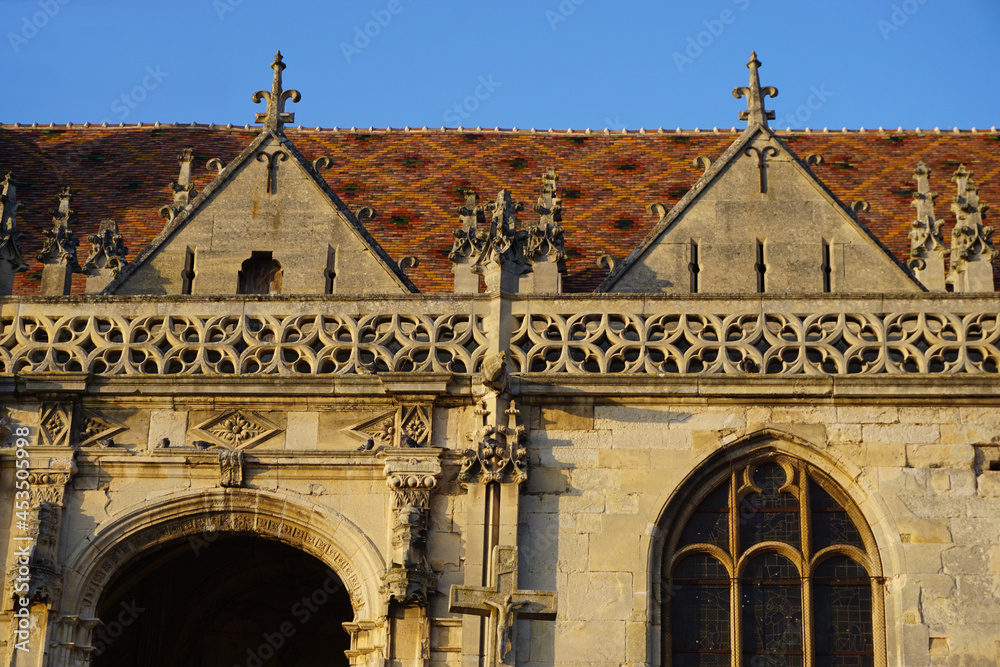 Obraz premium closeup facade old stone church intricate carvings colorful mosaic roof france