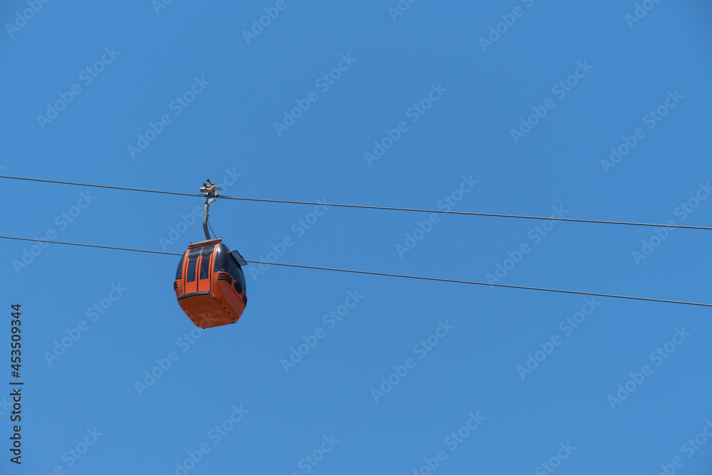 cable car carrying passengers from above. blue sky background. 
