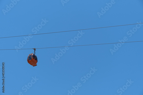 cable car carrying passengers from above. blue sky background. 