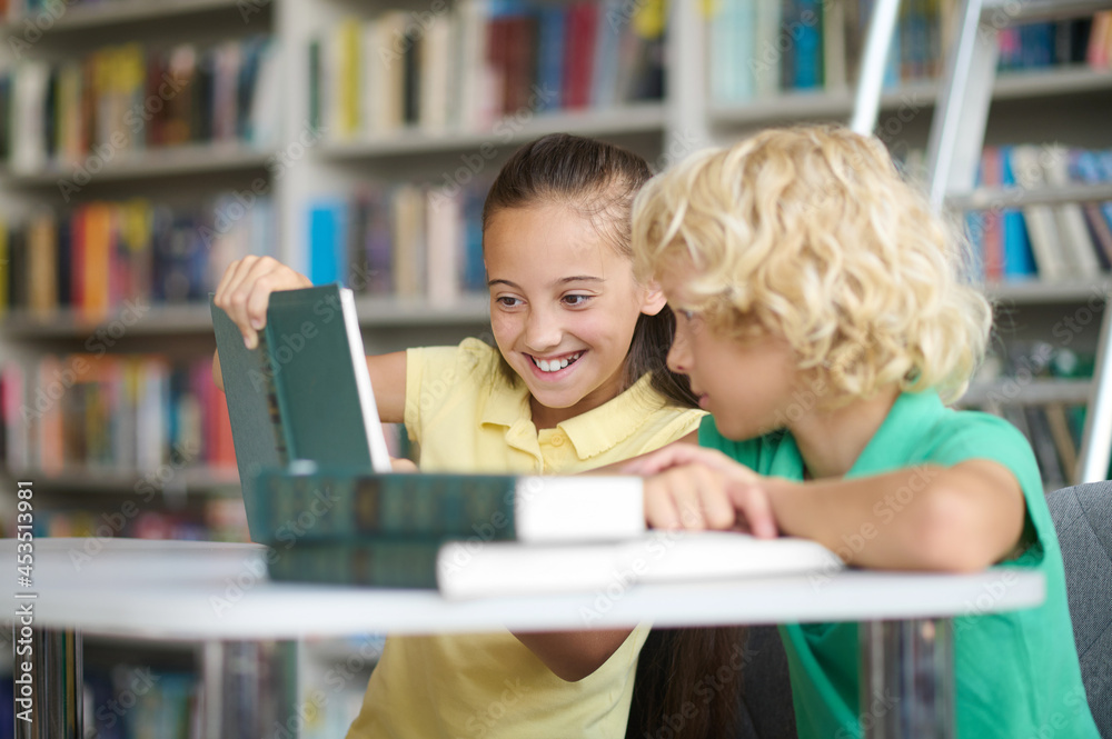 Fototapeta premium Two classmates doing their homework at the library desk