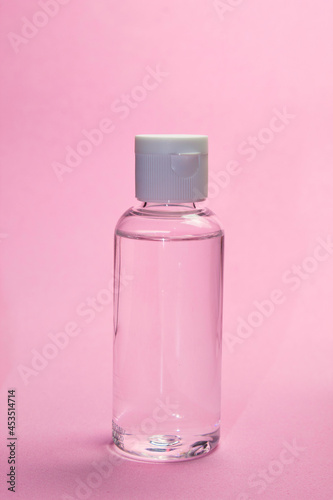 Bote de gel hidroalcoholico con fondo rosa vertical para la desinfección de manos, protección ante el coronavirus. photo