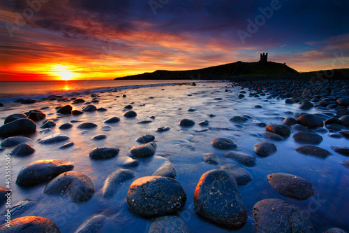 Sunrise at Embleton Beach with Dunstanburgh Castle in the background, Northumberland, England, UK. photo