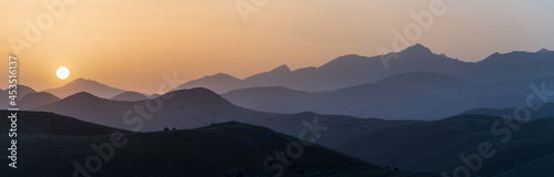 Sunset view point on rocky mountains silhouette. Campo Imperatore  Gran Sasso  Apennines  Italy. Clear sky sun burst on dramatic mountain ridge.