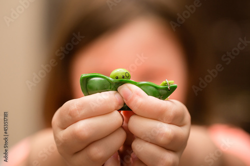 Fényképezés Girl's hands playing with green pea popper sensory fidget toy