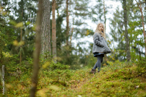 Cute young girl having fun on beautiful autumn day in a forest. Active family leisure with kids.