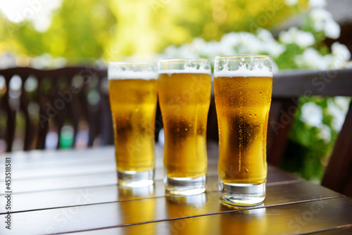 Three glasses of cold beer on a table in an outdoor restaurant.