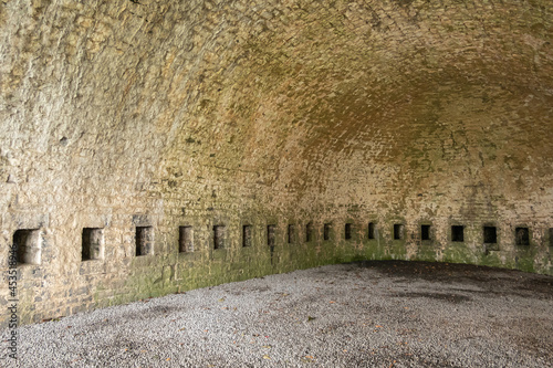 Dinant, Wallonia, Belgium - August 8, 2021: Citadel Fort. Beige brick stone undergroun storage place. Empty with dark niches.  photo