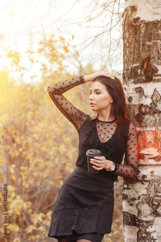 Portrait of pretty young woman in dark dress with in autumn
