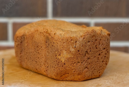 Loaf of homemade freshly baked bread on brown brick wall background