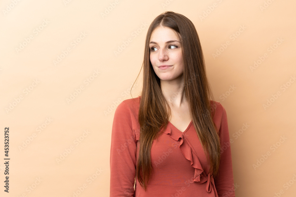 Young caucasian woman isolated on beige background having doubts while looking side Young caucasian woman isolated on beige background having doubts while looking side