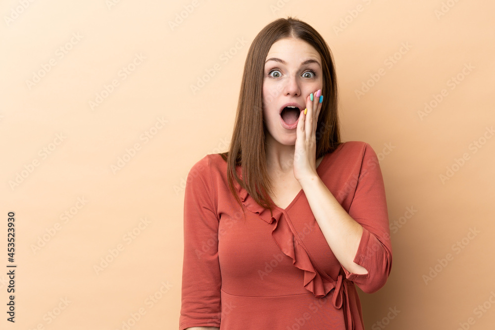 Young caucasian woman isolated on beige background with surprise and shocked facial expression Young caucasian woman isolated on beige background with surprise and shocked facial expression