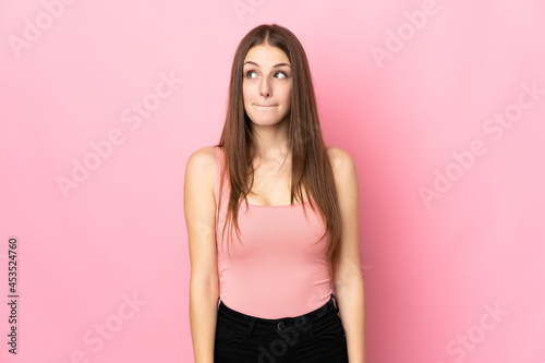 Young caucasian woman isolated on pink background having doubts while looking up