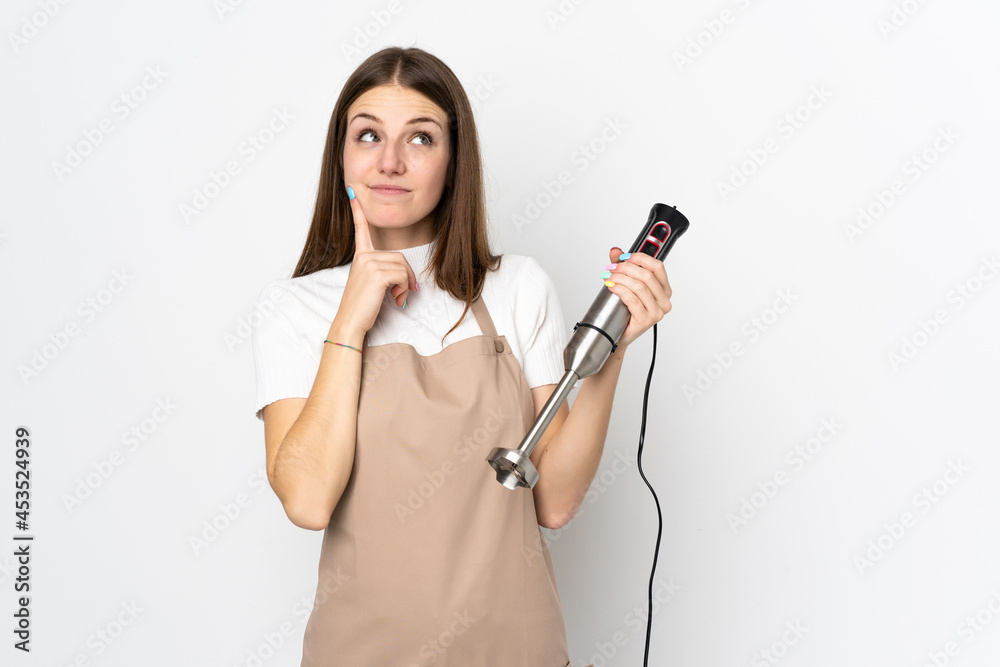 Young woman using hand blender isolated on white background thinking an idea Young woman using hand blender isolated on white background thinking an idea