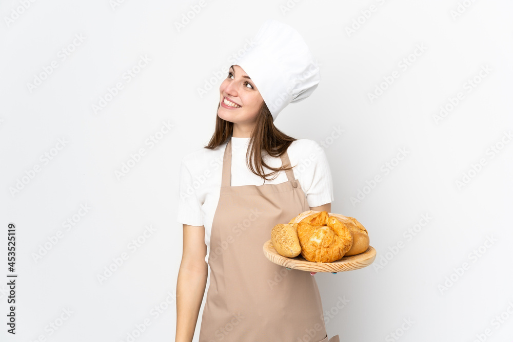 Young woman in chef uniform isolated on white background laughing and looking up Young woman in chef uniform isolated on white background laughing and looking up