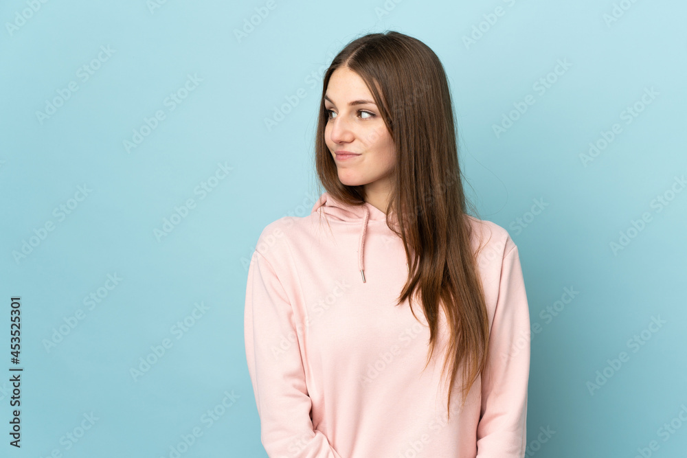 Obraz premium Young caucasian woman isolated on blue background having doubts while looking side