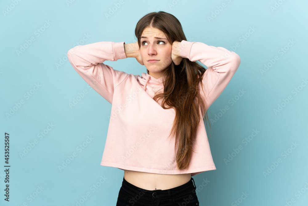 Fototapeta premium Young caucasian woman isolated on blue background frustrated and covering ears