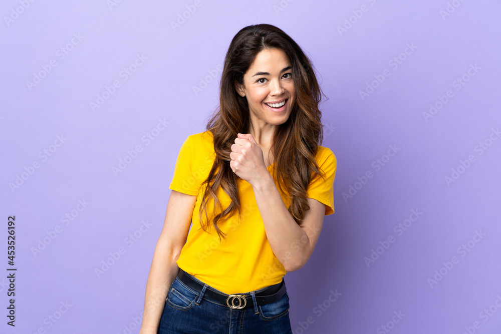 Woman over isolated purple background celebrating a victory Woman over isolated purple background celebrating a victory