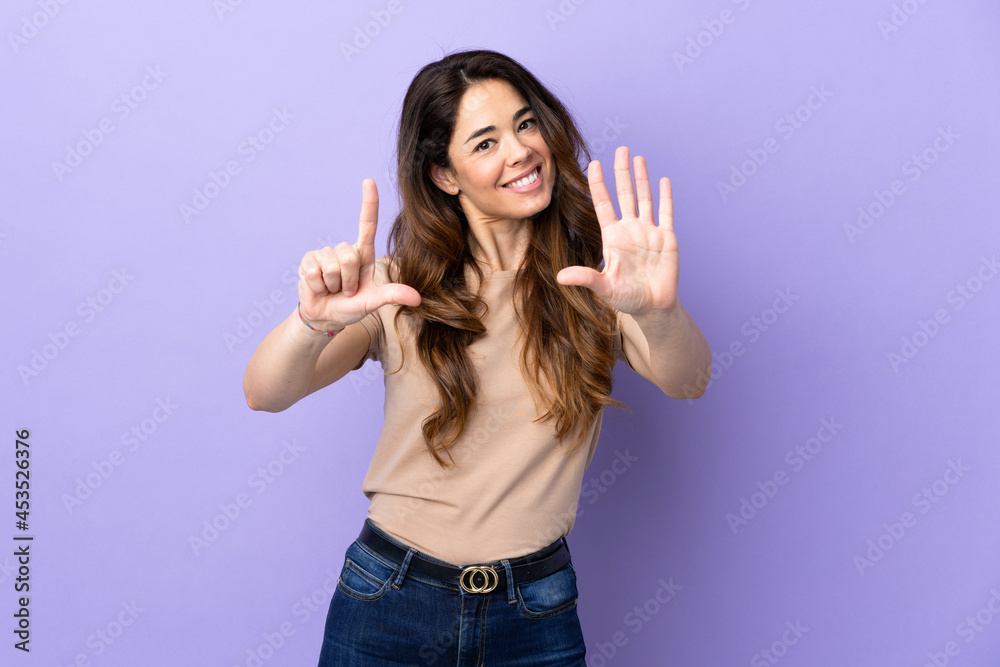 Woman over isolated purple background counting seven with fingers