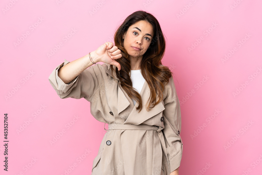Woman over isolated background showing thumb down with negative expression Woman over isolated background showing thumb down with negative expression