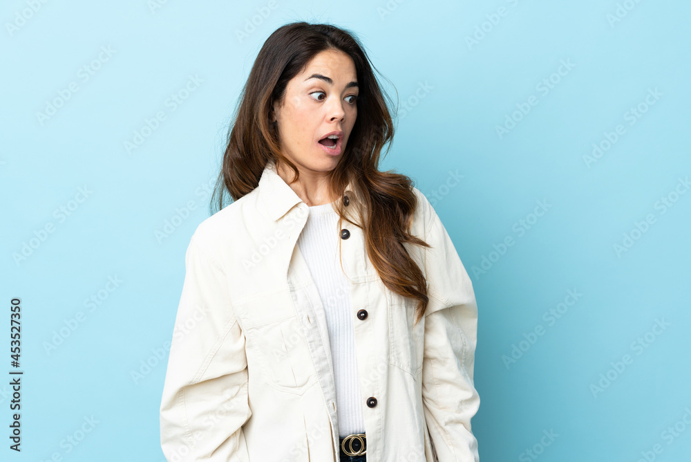 Woman over isolated background doing surprise gesture while looking to the side Woman over isolated background doing surprise gesture while looking to the side