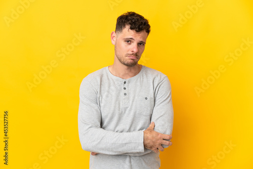 Young caucasian handsome man isolated on yellow background with sad expression
