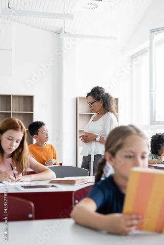 african american teacher talking to asian schoolboy during lesson © LIGHTFIELD STUDIOS