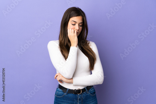 Teenager Brazilian girl over isolated purple background having doubts