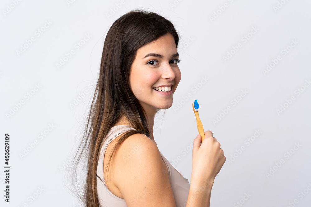 Teenager Brazilian girl brushing her teeth over isolated white background Teenager Brazilian girl brushing her teeth over isolated white background