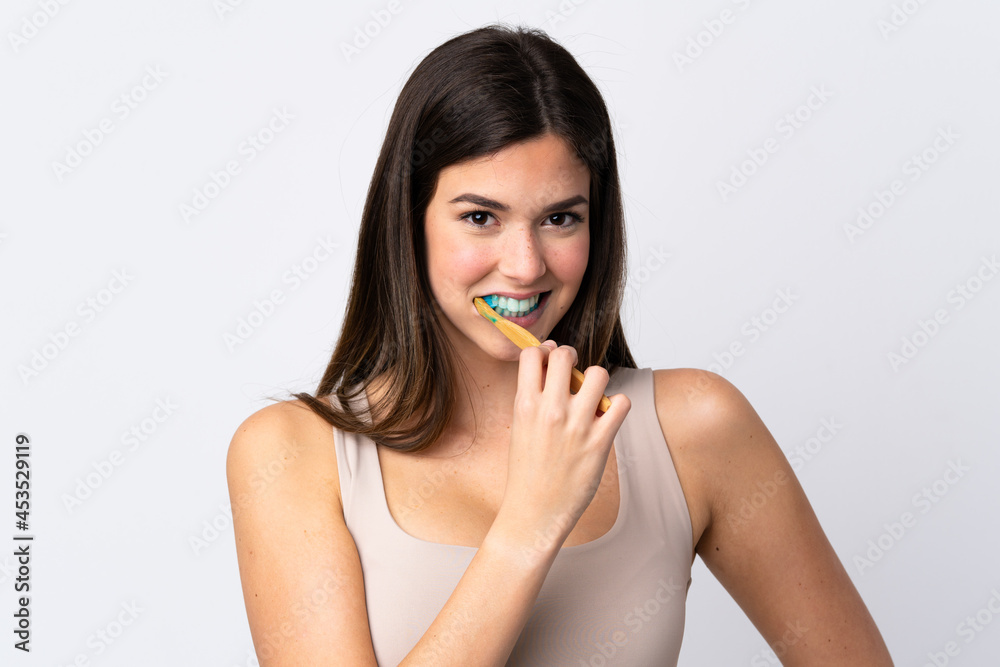 Teenager Brazilian girl brushing her teeth over isolated white background Teenager Brazilian girl brushing her teeth over isolated white background