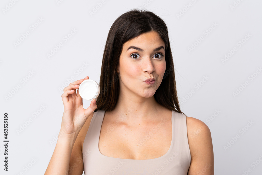 Teenager Brazilian girl with moisturizer over isolated white background Teenager Brazilian girl with moisturizer over isolated white background