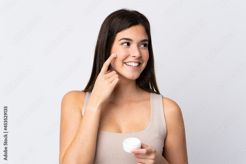 Teenager Brazilian girl with moisturizer over isolated white background Teenager Brazilian girl with moisturizer over isolated white background