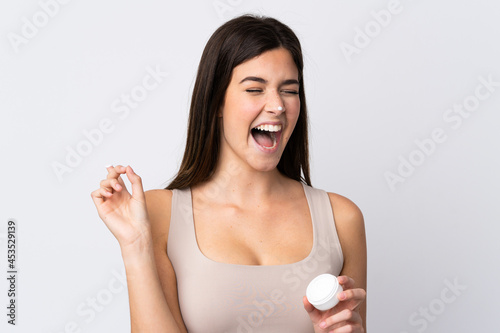 Teenager Brazilian girl with moisturizer over isolated white background