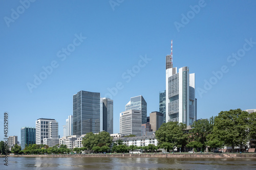 Outdoor sunny view of cityscape and promenade of riverside Main river in Frankfurt, Germany during sunny day.
