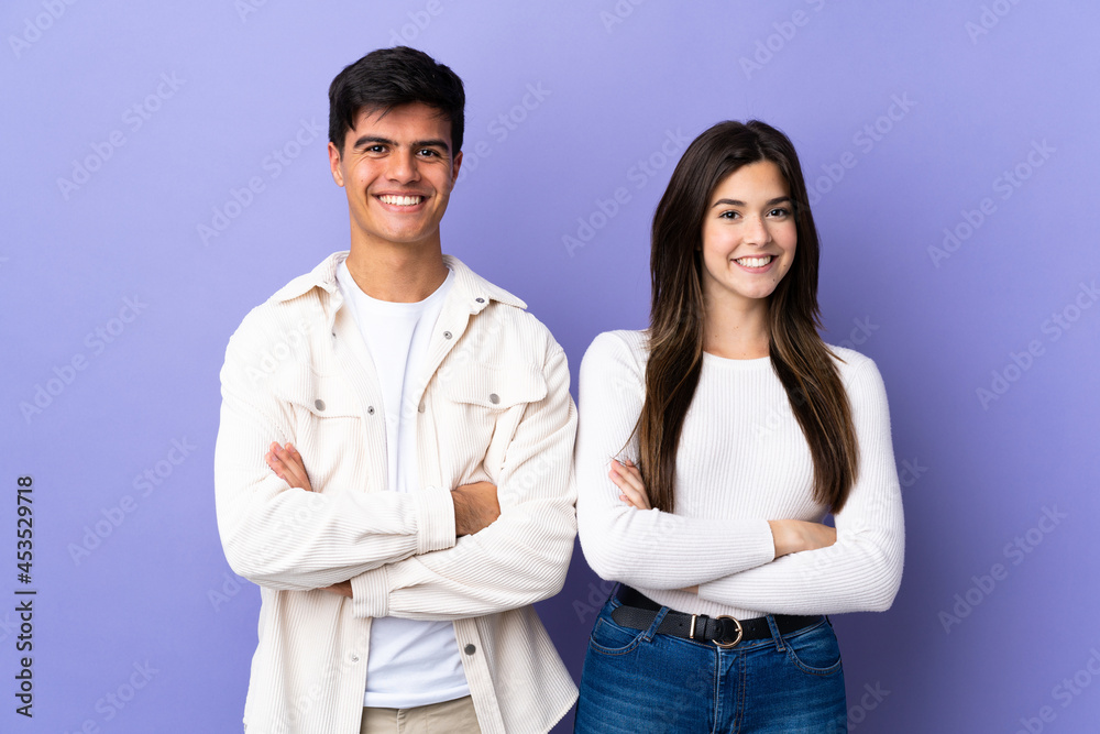 Young couple over isolated purple background keeping the arms crossed Young couple over isolated purple background keeping the arms crossed