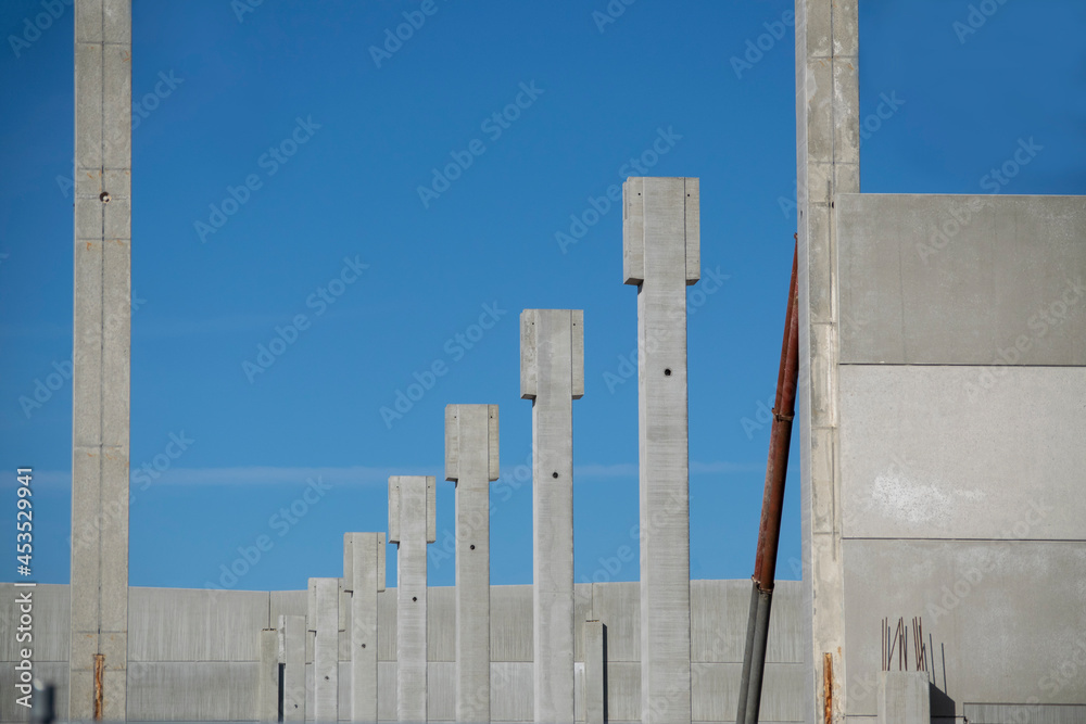 Cranes and lifts carrying concrete walls for installation on a warehouse and office construction site