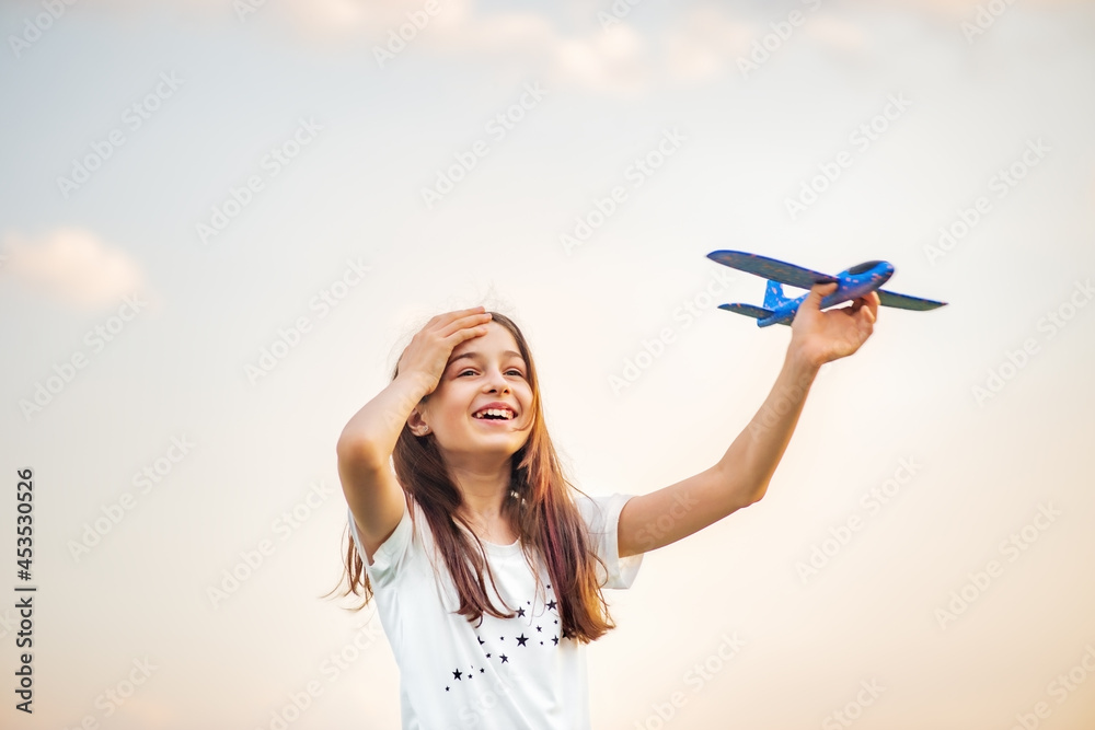 Young teenage girl holding airplane. freedom. Toy plane on the background of the sky in hand Young teenage girl holding airplane. freedom. Toy plane on the background of the sky in hand