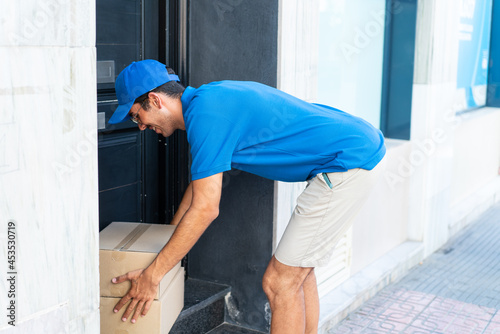 Young delivery man at outdoors leaving the boxes at the door