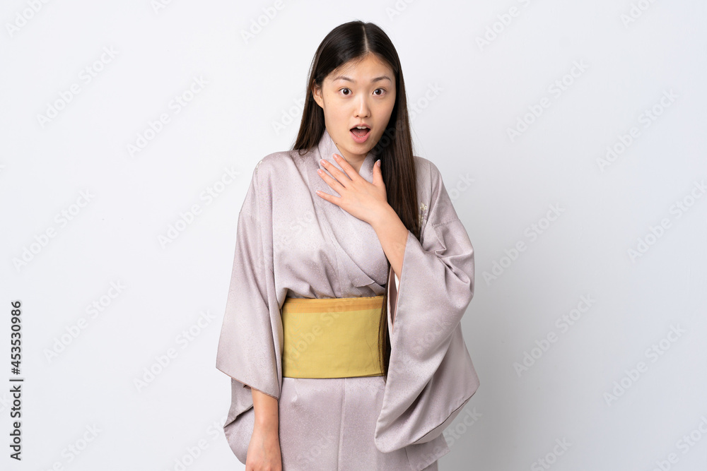 Young Chinese girl wearing kimono over isolated background surprised and shocked while looking right Young Chinese girl wearing kimono over isolated background surprised and shocked while looking right