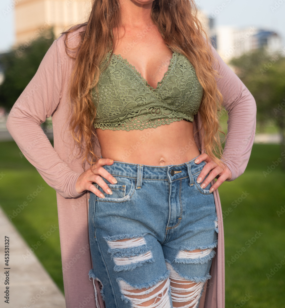 Sexy Woman Wearing a Lace Bralette Top Ripped Jeans with Her Hands on Her  Hips Stock Photo | Adobe Stock
