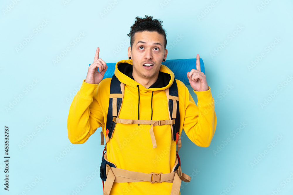 Young mountaineer man with a big backpack over isolated blue background pointing with the index finger a great idea Young mountaineer man with a big backpack over isolated blue background pointing with the index finger a great idea
