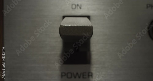 Power Switch ON/OFF. Macro extreme close up on a vintage silver brushed metal stereo system as the power switch flips on and off.