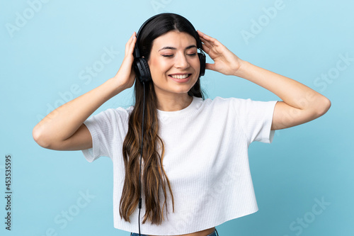 Young brunette girl over isolated blue background listening music