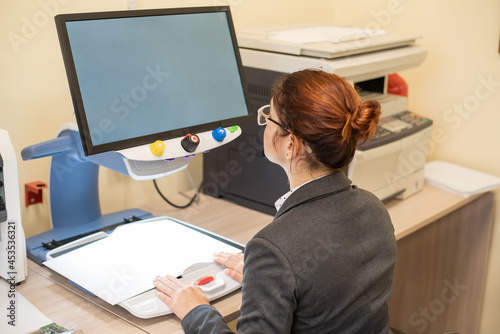 Foto A visually impaired woman uses special reading equipment