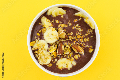 Brazilian açai in a white bowl with banana, granola and chestnuts.